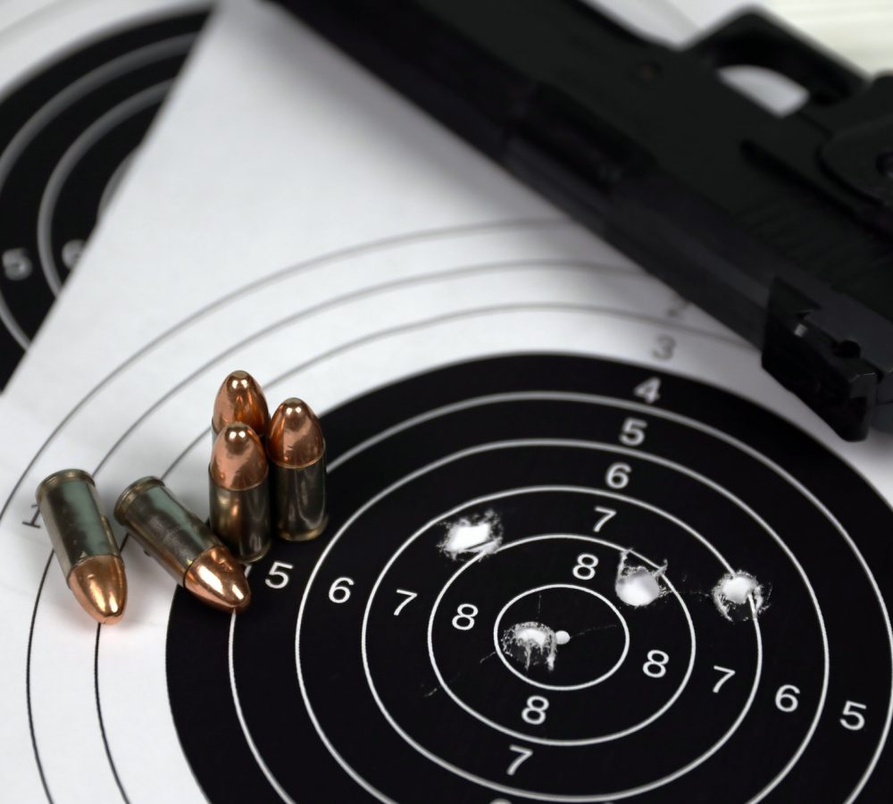 gun-and-many-bullets-shooting-targets-on-white-table-in-shooting-range-polygon-training-for-aiming.jpg